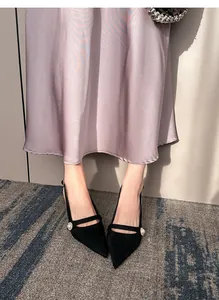 Detalle de zapatos slingback de ante negro con punta fina y perla