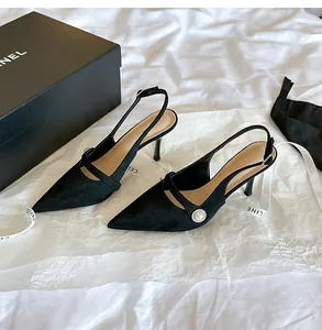 Vista lateral de elegantes tacones de ante negro con una hebilla de perla decorativa
