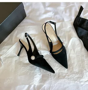 Vista detallada de elegantes zapatos slingback de ante negro con punta y hebilla de perlas.