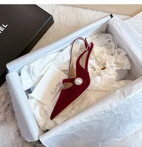 Detalle de elegantes zapatos slingback de terciopelo rojo con punta en una caja blanca
