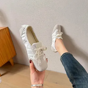 Nahaufnahme von weiß-grauen Ballett-Sneakern aus Leder mit Drei-Streifen-Design-Details.