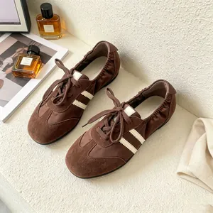 Nahaufnahme von braunen Leder-Ballerinas mit weißen Streifen und Schnürung