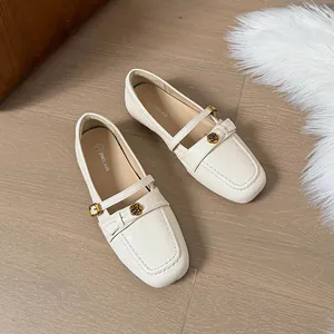 Close-up of cream white flat Mary Jane loafers with rose embellishment and strap