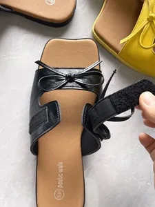 Detailaufnahme der schwarzen Retro-Plateau-Sandale mit Klettverschluss und Schleife.