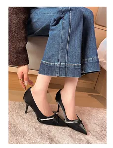 Modelo luciendo tacones de aguja negros de punta con detalle de cadena de perlas.