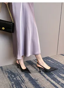Elegantes zapatos de tacón destalonados de raso negro con punta fina y falda de satén