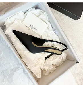 Elegantes zapatos de tacón destalonados de satén negro en caja de regalo blanca.