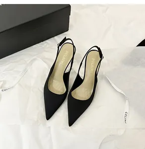 Detalle de elegantes zapatos de tacón aguja tipo slingback en raso negro con punta afilada
