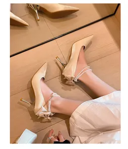 Vista detallada de tacones de novia en satén champán con elegantes correas de perlas