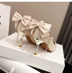 Elegantes zapatos de tacón en satén con lazo y cadena de perlas para novia.