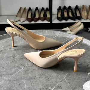 Detalle de elegantes zapatos de tacón en satén beige con punta fina y tira trasera.