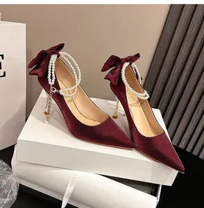 Primer plano elegante de zapatos de novia de satén granate con perlas y detalle de lazo