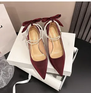 Elegantes salones de satén granate con tiras de perlas y lazos sobre cajas de regalo.