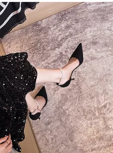 Detail view of black suede pointed-toe pumps with elegant pearl ankle straps.