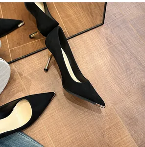 Primer plano de elegantes tacones de ante negro con punta metálica y tacón dorado