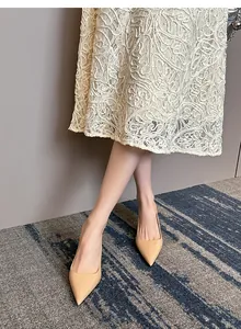 Elegant nude patent leather pointed-toe stiletto pumps on model with lace dress detail