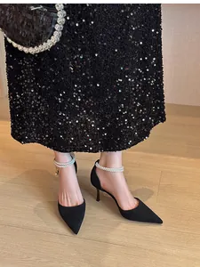 Detail view of black suede pointed-toe heels with elegant pearl ankle straps