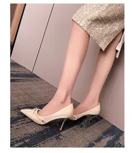 Detalle de elegantes zapatos beige de punta con cadena de perlas y tacón de aguja
