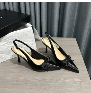 Dettaglio elegante di tacchi a spillo in vernice nera con punta e fiocco decorativo.