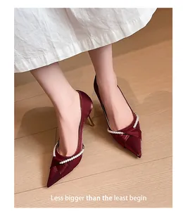 Detalle de zapatos franceses de tacón burdeos con punta y elegante cadena de perlas