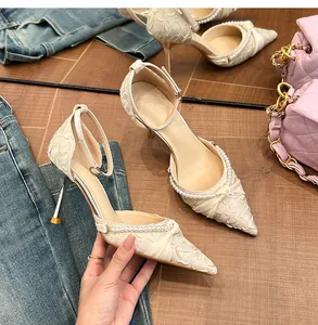 Detalle de zapatos de tacón con punta fina, adornos de perlas y correa al tobillo.