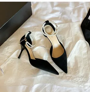 Close-up of black suede pointed toe high heels featuring elegant pearl ankle strap.
