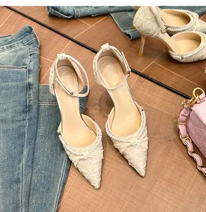 Detalle de tacones de punta crema con cuentas de perlas y textura de tela plisada.