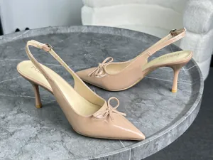 Primo piano di décolleté beige in vernice con punta a punta e fiocco decorativo