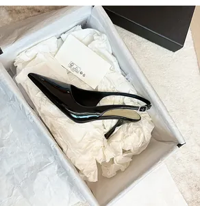 Detail view of glossy black patent leather slingback stiletto heels inside a premium shoebox