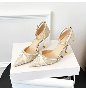 Detalle de zapatos beige de punta con pliegues, tira de perlas y adorno de lazo elegante