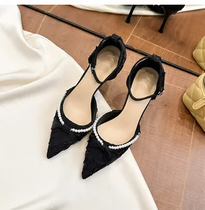 Detalle de zapatos de tacón negros con adornos de perlas y lazo