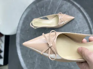 Primo piano dell'elegante scarpa in vernice nude con punta e dettaglio a fiocco raffinato.