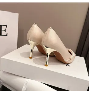 Detalle de tacones franceses champán con cadena de perlas y elegante tacón de aguja metálico.