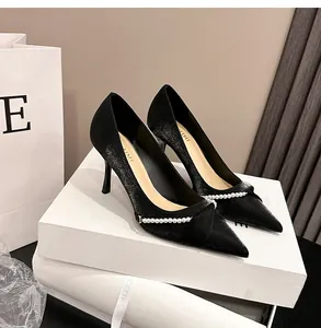 Vista detallada de elegantes zapatos de tacón negros con punta y cadena de perlas