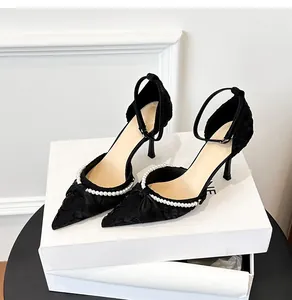 Detalle de salones negros de punta con tira de perlas y hebilla.