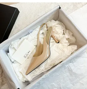 Detail showing a nude patent leather slingback pump with pointed toe in a shoe box.