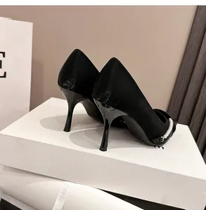 Vista detallada de stilettos negros de punta con una elegante cadena de perlas