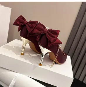 Elegantes tacones de satén rojo vino con lazo grande y detalle de cadena de perlas
