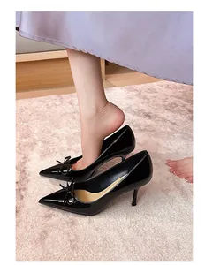 Nahaufnahme von eleganten schwarzen Lackleder-Stilettos mit einem schicken Schleifendetail.