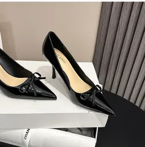 Detailansicht von schwarzen Lackleder-Pumps mit spitzer Zehenpartie und Dekoschleife