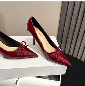 Nahaufnahme eleganter weinroter Lackleder-Pumps mit spitzer Kappe und Schleifendetail