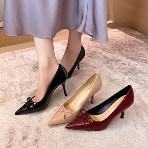 Elegante Stöckelschuhe mit spitzer Kappe und Schleife aus glänzendem Lackleder.