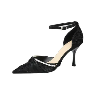 Elegantes tacones negros de punta con ribete de perlas y correa al tobillo para mujer.
