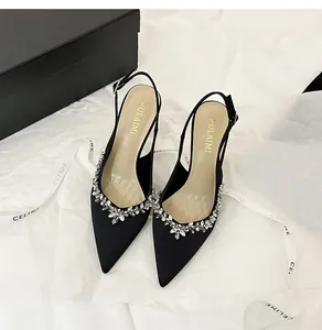 Dettaglio delle scarpe slingback in raso nero con eleganti fiori di strass luccicanti.