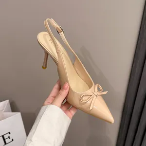 Primo piano di décolleté in vernice beige a punta con fiocco e tacco a spillo sottile