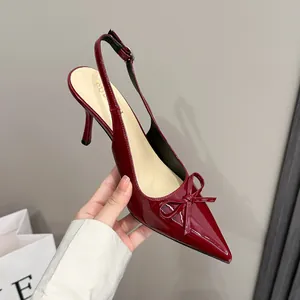 Dettaglio di scarpa slingback in vernice rosso vino con punta affilata e fiocco.