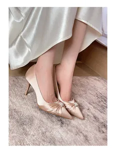 Details von champagnerfarbenen Satin-Pumps mit eleganten Falten und Perlenschnalle.