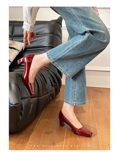 Dettaglio di eleganti scarpe décolleté in vernice bordeaux con punta quadrata e tacco largo.