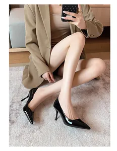 Elegant black patent leather pointed-toe stiletto pumps worn by a model in a lifestyle setting.