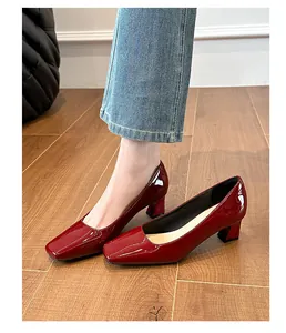 Primo piano di décolleté bordeaux in vernice con punta quadrata e tacco largo indossate